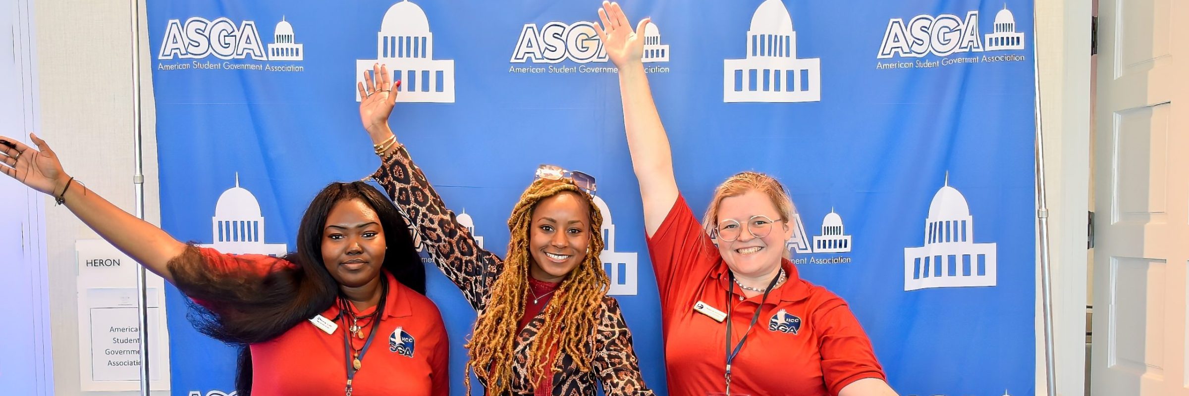 Three student government leaders smiling and waving at an ASGA conference